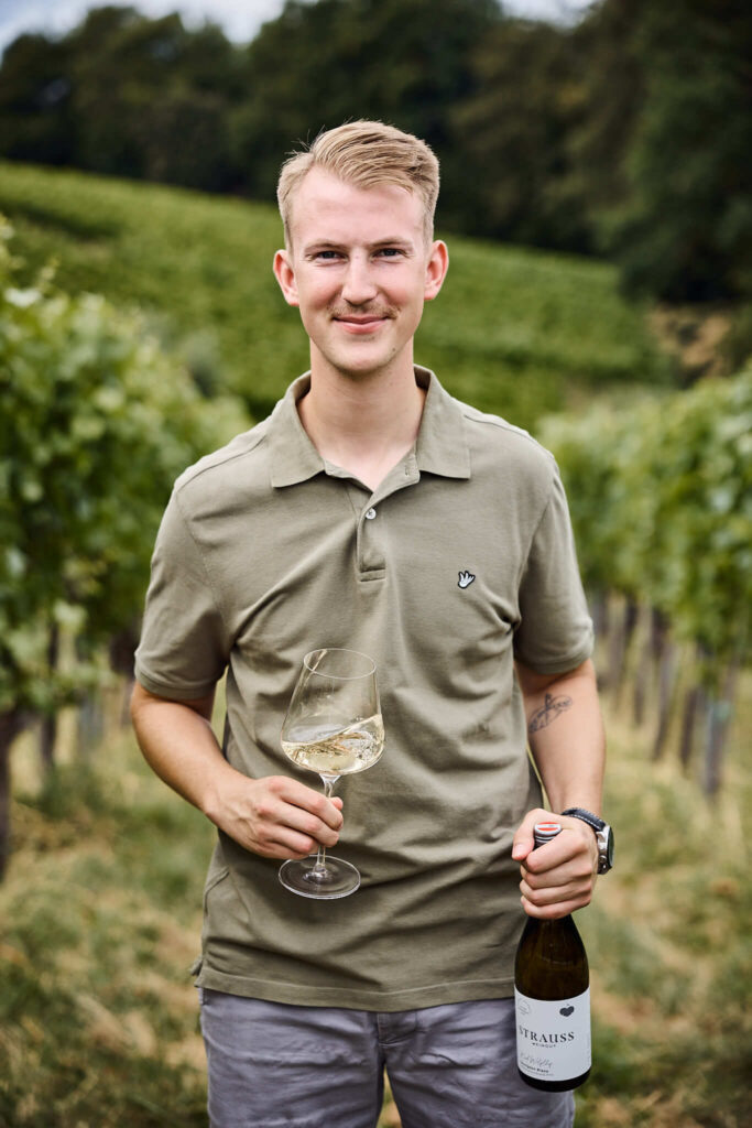 Porträt Matthias Strauss mit Weinglas und Weinflasche - Weingut Strauss