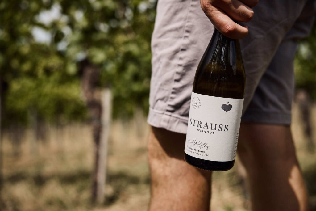 Weinflasche im Fokus - Matthias Strauss hält Premium-Wein von Weingut Straus