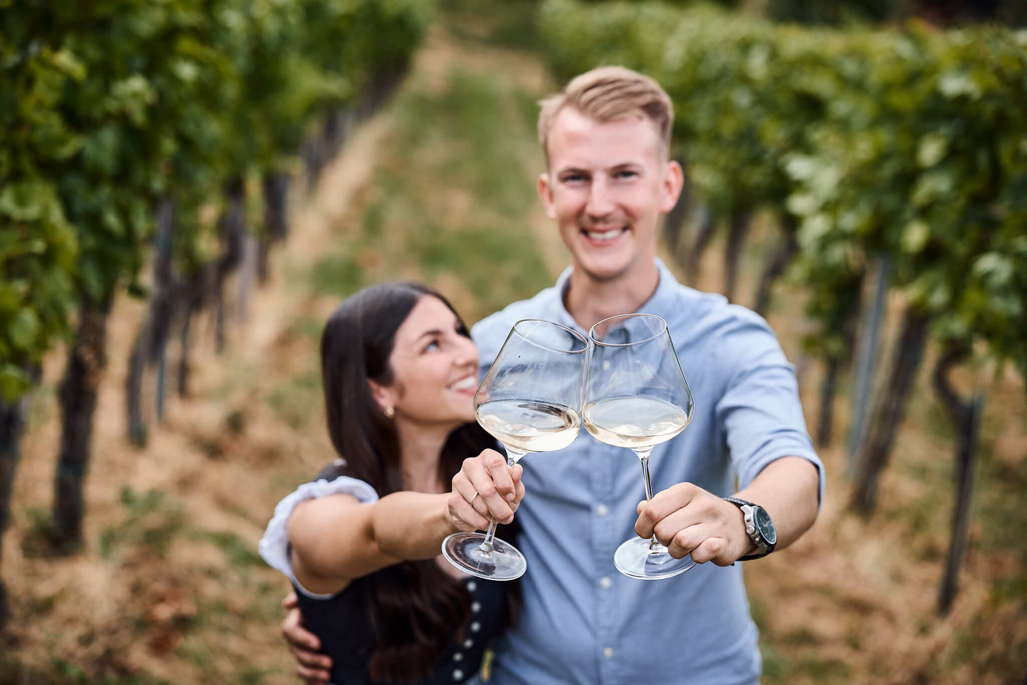 Paar stößt mit Weingläsern an - Matthias Strauss und Partnerin genießen Wein von Weingut Strauss