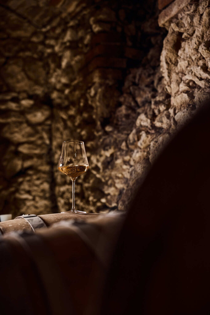 Nahaufnahme von Weinglass auf Holzfass im Weinkeller